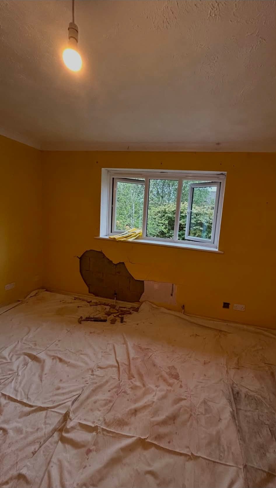 The same bedroom freshly replastered, floor protected with dust sheets