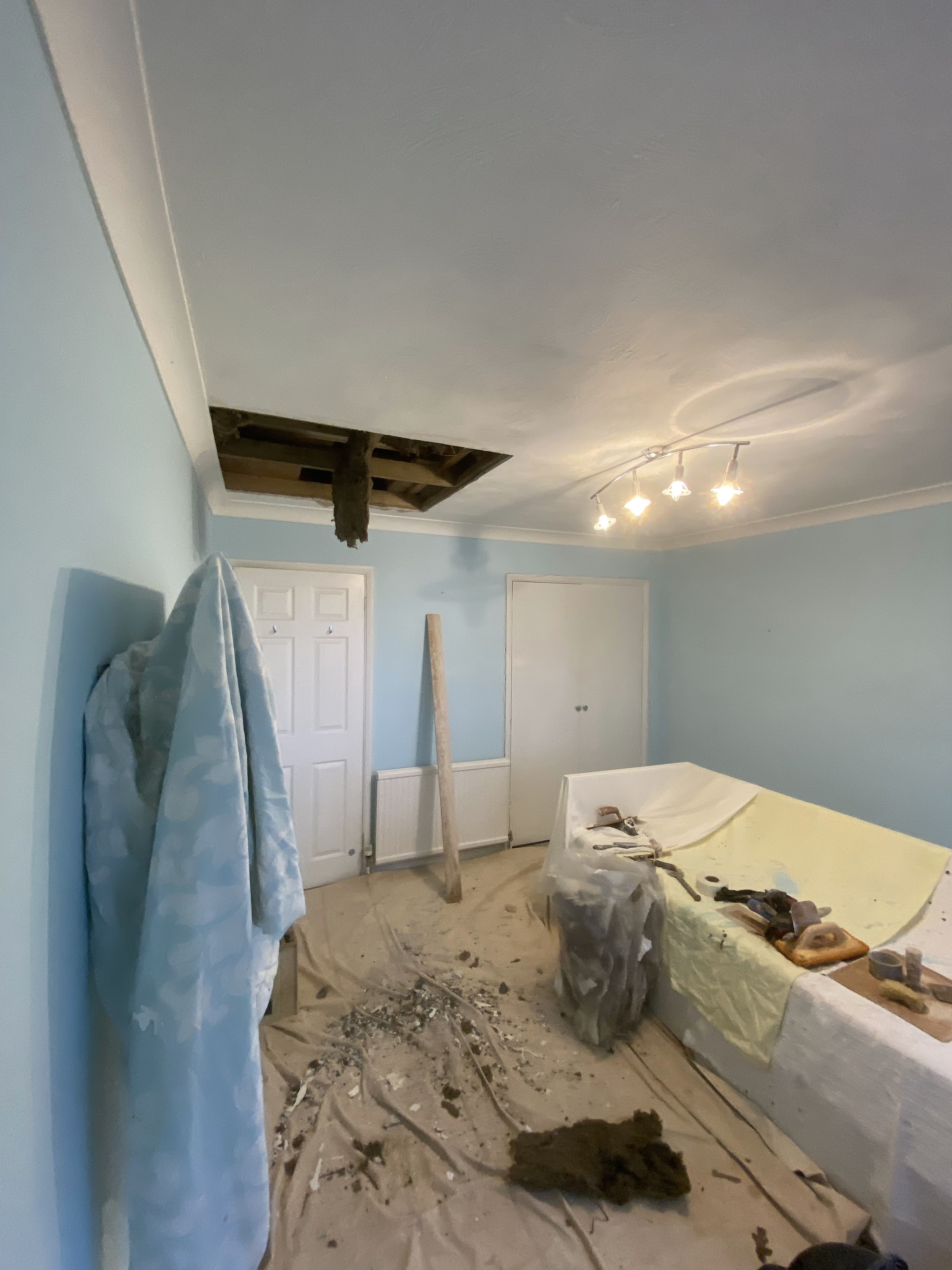 Bedroom ceiling opened up for repair, furniture covered