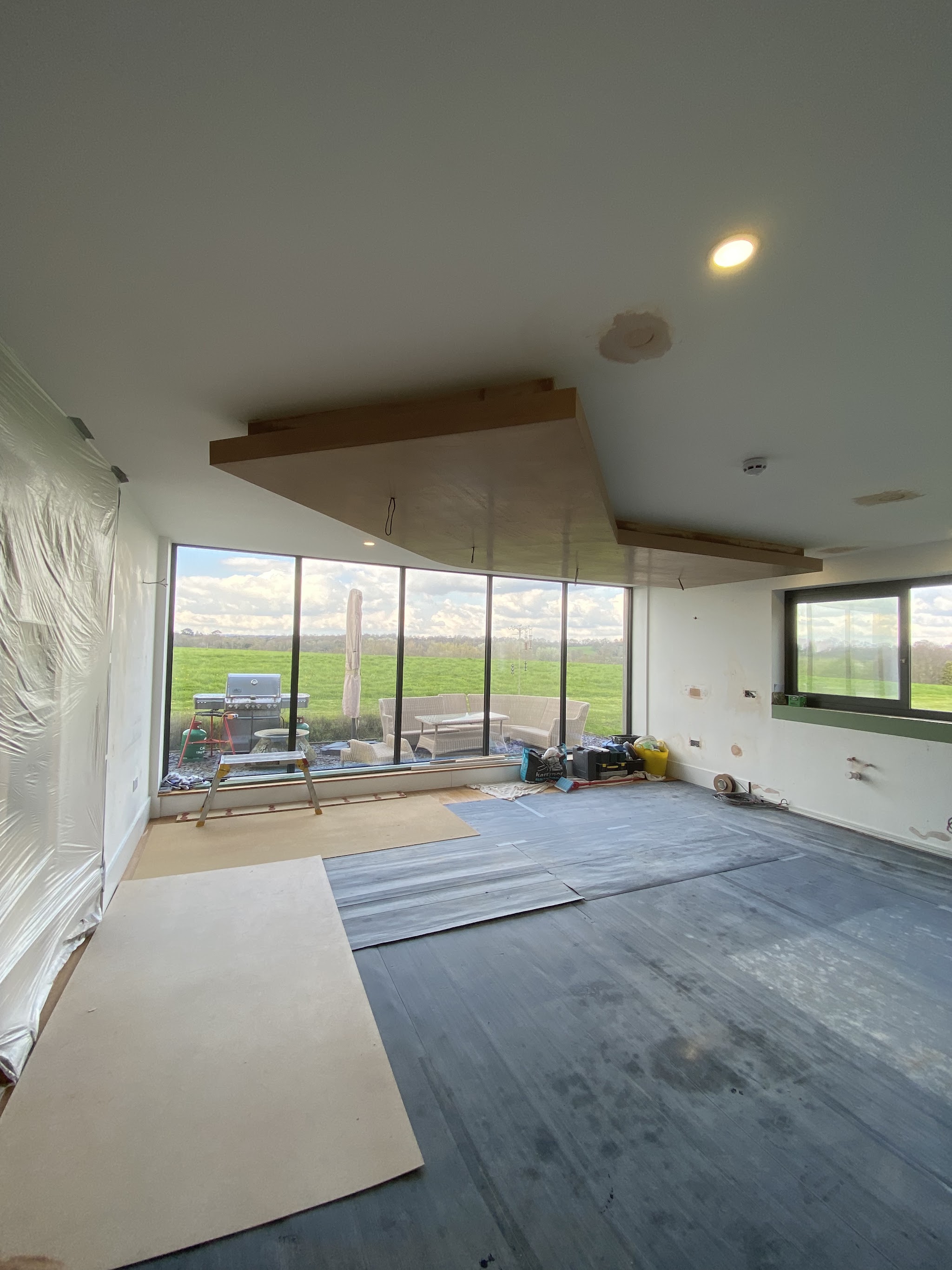 Open room with large windows, ceiling boarded ready for plaster