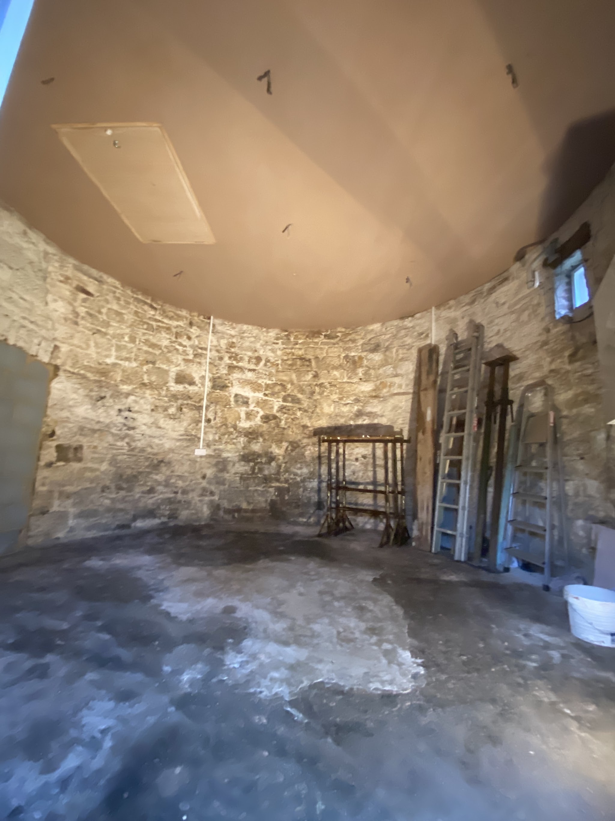 Round stone-walled room with a newly plastered ceiling
